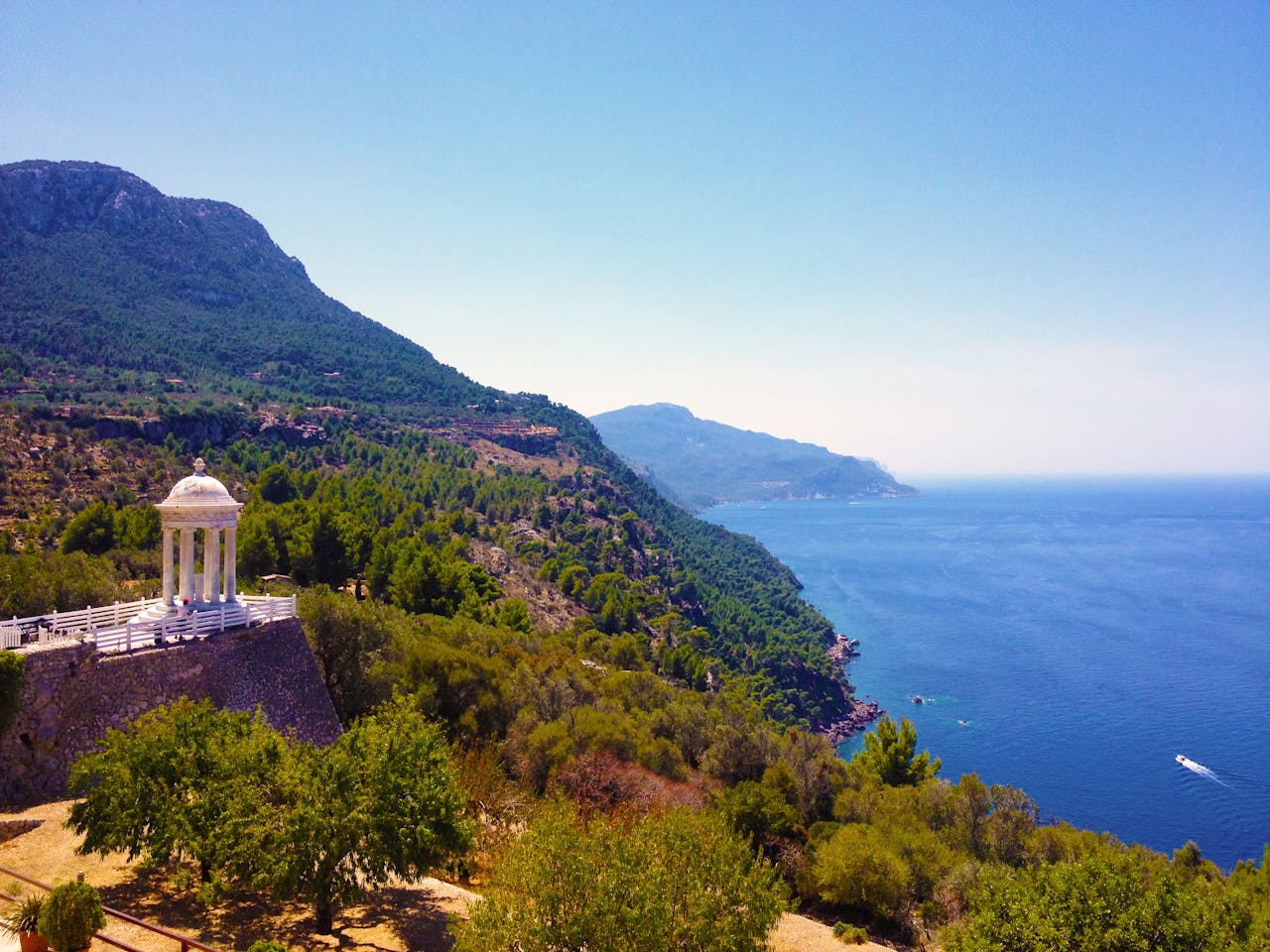 team-02 Breathtaking view of Mallorca's coastline featuring a peaceful pergola with lush greenery and azure ocean.